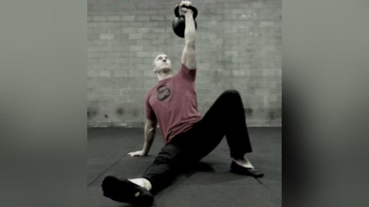 Man gripping a kettlebell in a Turkish Get-Up position