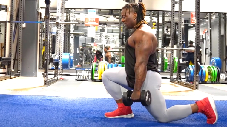 A person kneeling in the dumbbell split squat starting position.