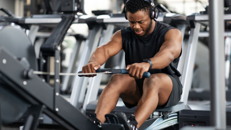 Muscular person in gym using rowing machine