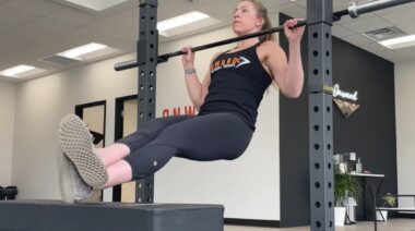 Long-haired person in gym doing pull-up exercise
