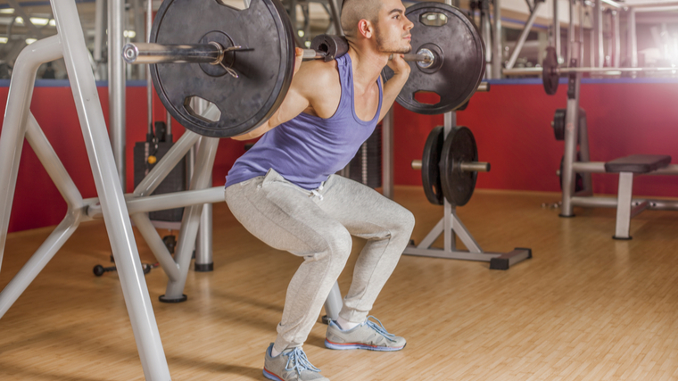 person in gym doing partial rep squats
